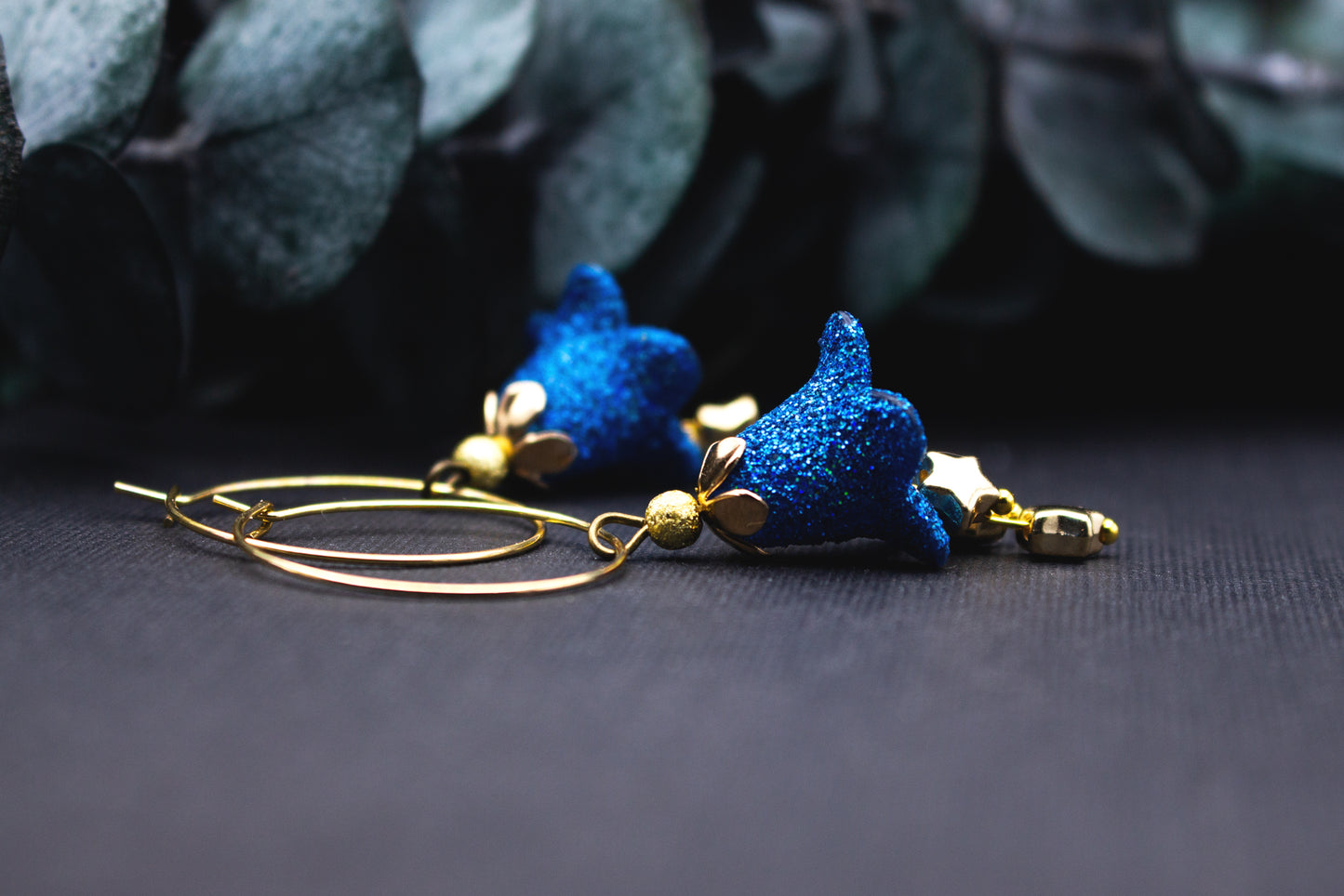 Detailansicht: blaues Glitzer-Sternchen an goldener Creole mit kleiner goldener Perle