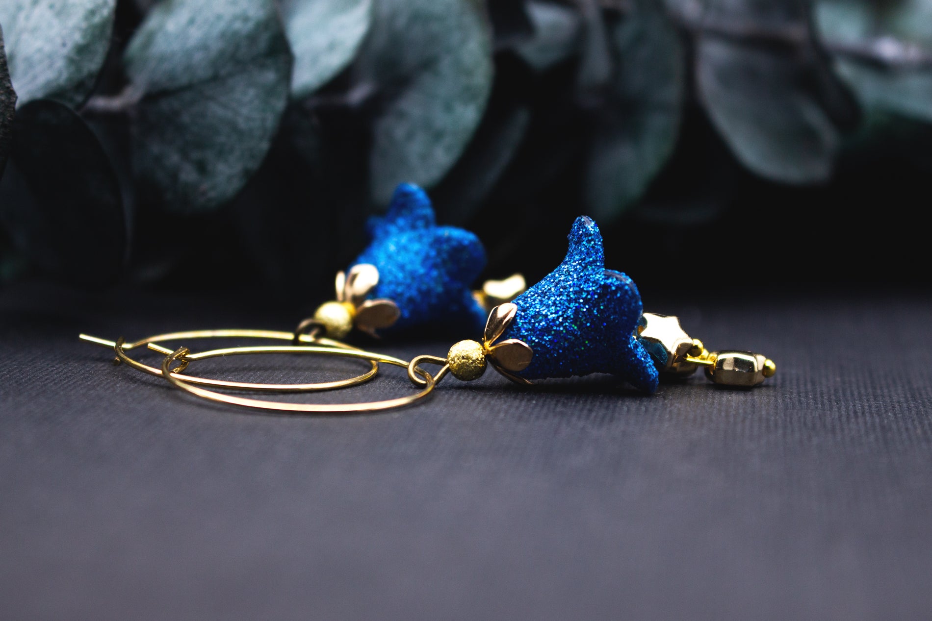 Detailansicht: blaues Glitzer-Sternchen an goldener Creole mit kleiner goldener Perle