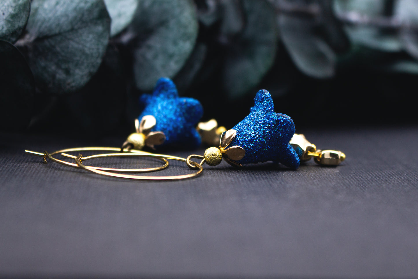 Creolen Ohrringe in Gold mit blau glitzernden Sternanhängern und Perlendetail