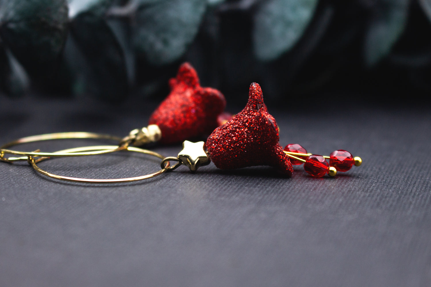 Creolen Ohrringe in Rot mit glitzernder Blütenform, kleinem goldfarbenem Stern und roten Glasperlen, detailreiche Nahaufnahme mit warmem Goldton