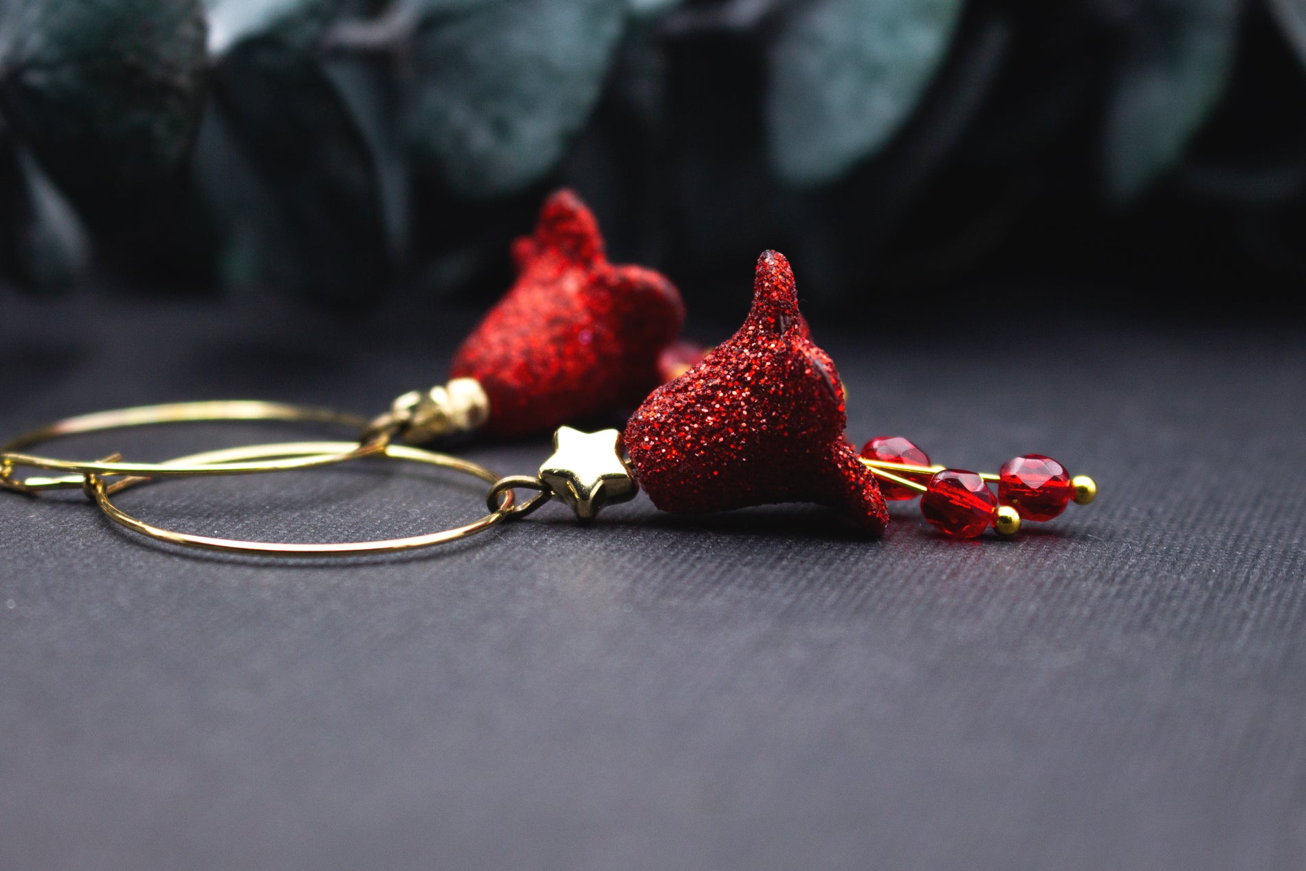 Creolen Ohrringe in Rot mit glitzernder Blütenform, kleinem goldfarbenem Stern und roten Glasperlen, detailreiche Nahaufnahme mit warmem Goldton