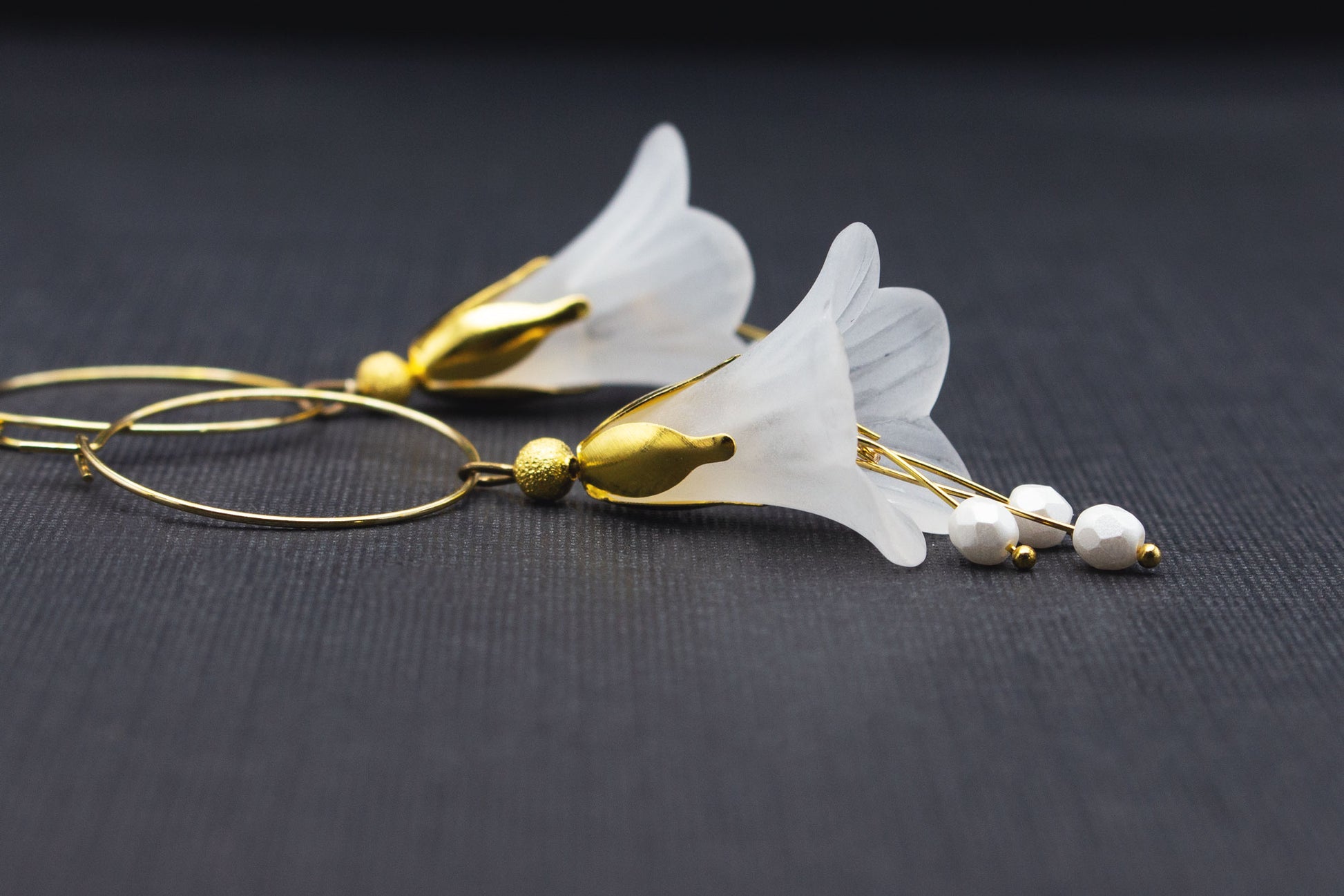 Detailaufnahme der weißen Blüten und Glasperlen an goldfarbenen Creolen