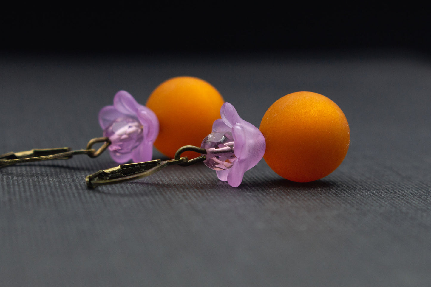 Detailansicht der Ohrringe mit Polaris-Perlen in Hellbraun und Blüten in Flieder, romantischer Schmuck