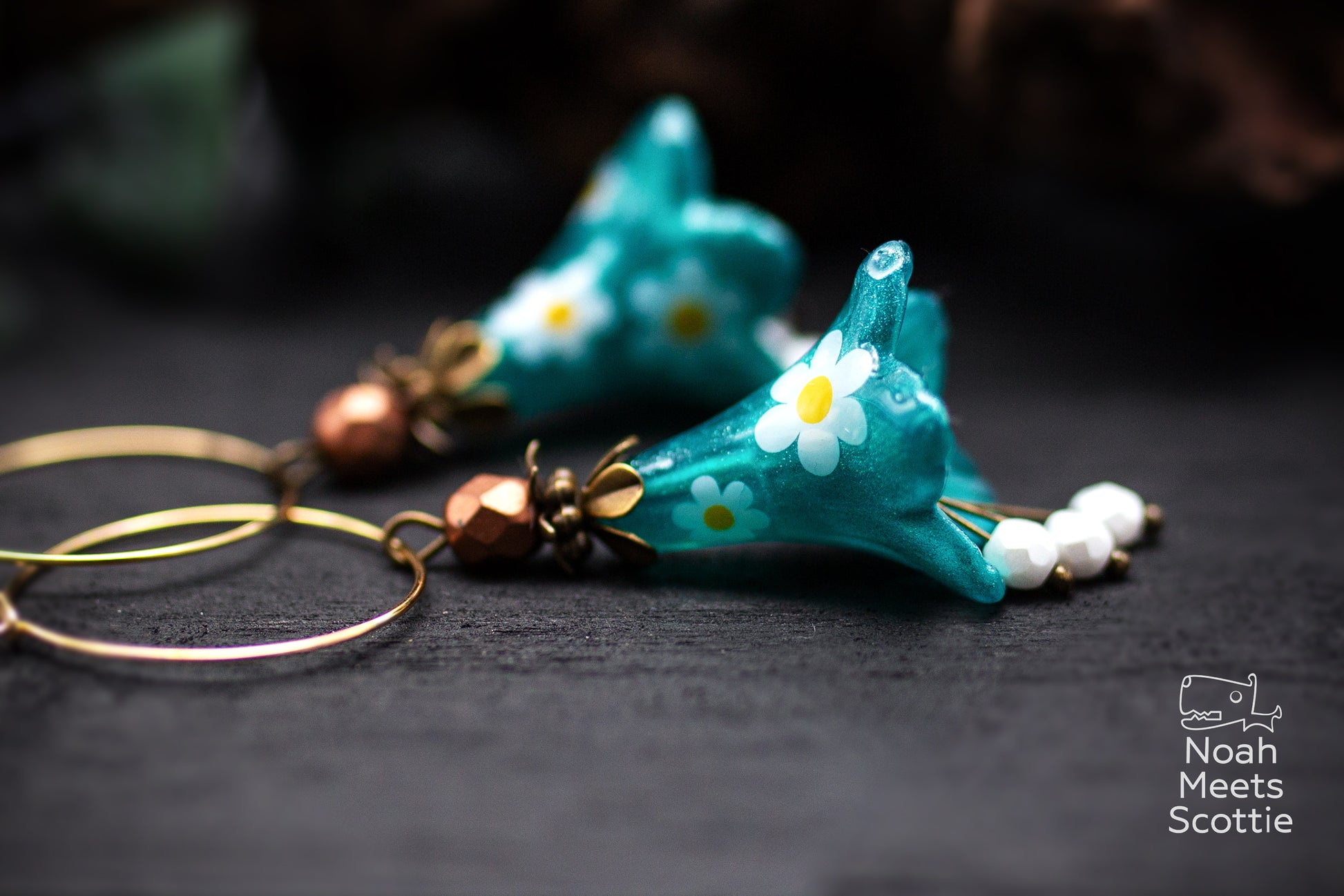 Florale Ohrringe mit glockenförmigen türkisen Blüten, weißen Gänseblümchen und facettierten Glasperlen.