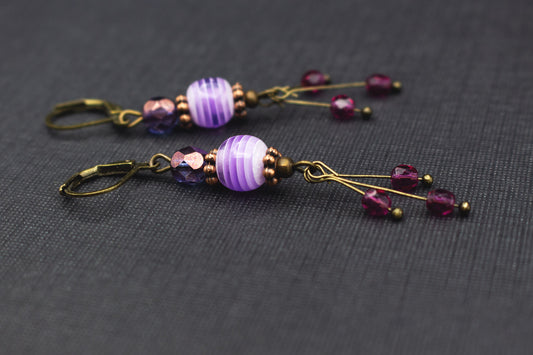 Ohrringe mit lila-weiß gestreiften Glasperlen, violetten Akzenten und Kupferdetails