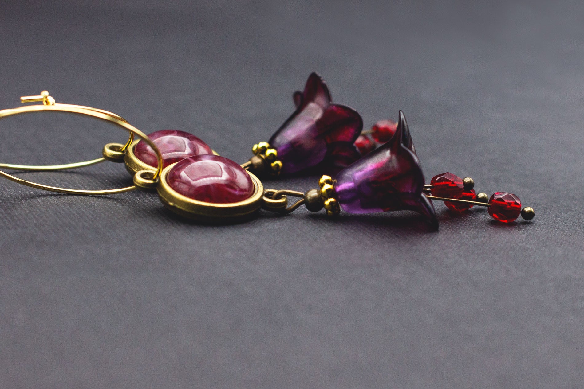Goldene Creolen mit dunkelrotem Cabochon, lila Blüten und roten Glasperlen