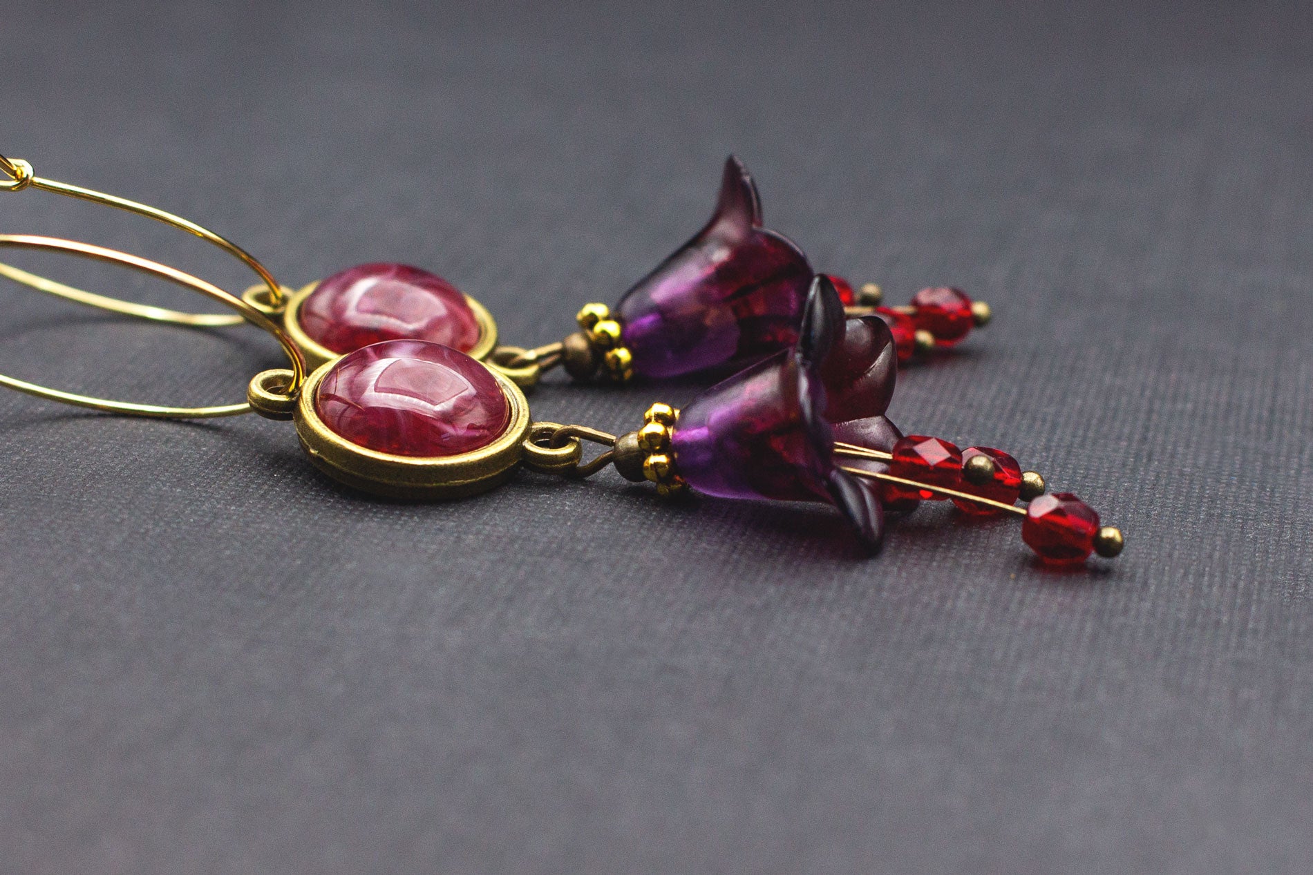 Seitenansicht goldene Creolen mit dunkelrotem Cabochon und lila Blüten