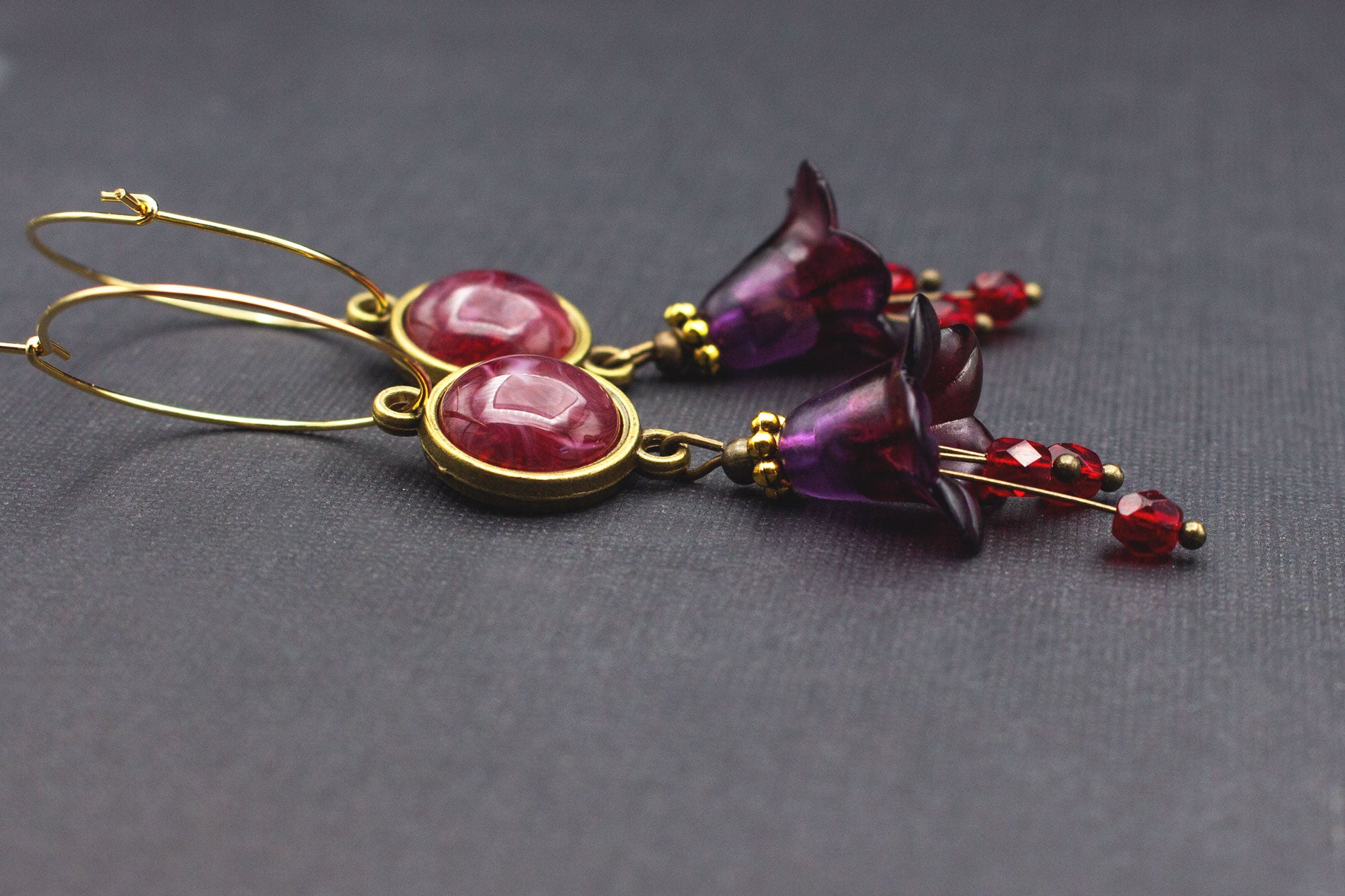 Detailansicht goldene Creolen mit dunkelrotem Cabochon und Glasperlen