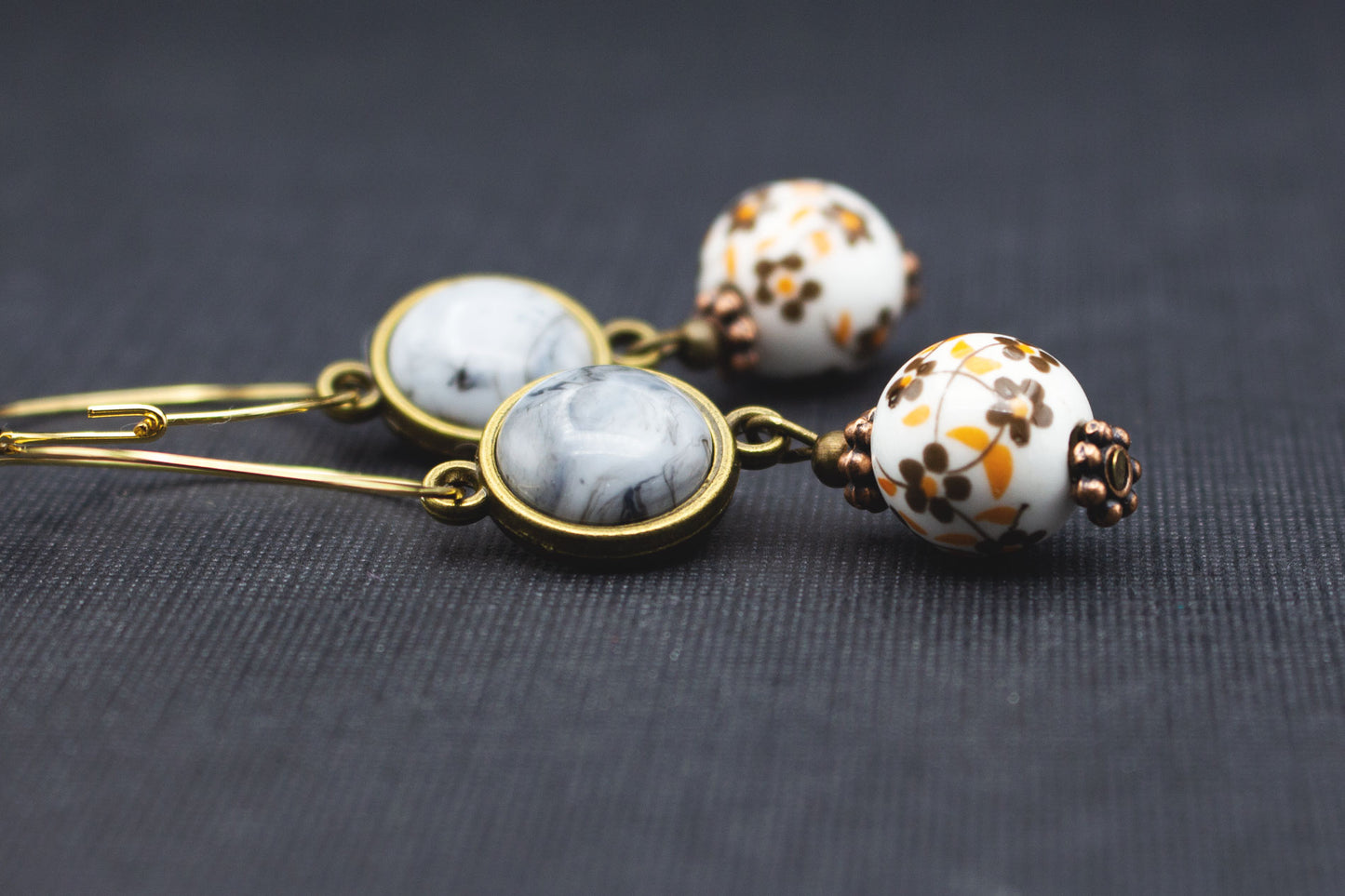 Detail goldfarbene Creolen mit grauen Cabochon-Perlen und floral verzierten Keramikperlen