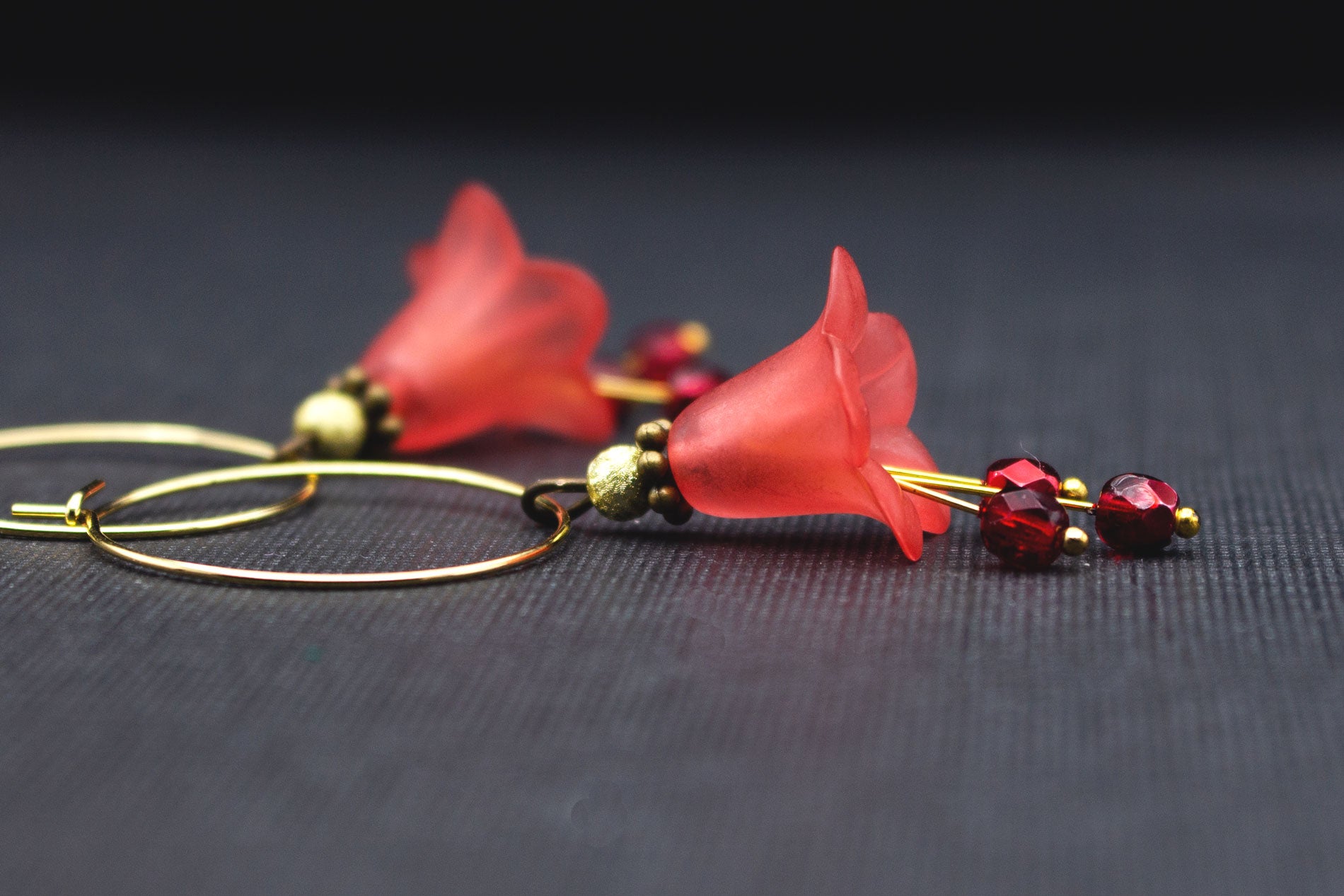 Detailaufnahme goldfarbene Creolen mit roten Acrylblüten und tiefroten Glasperlen
