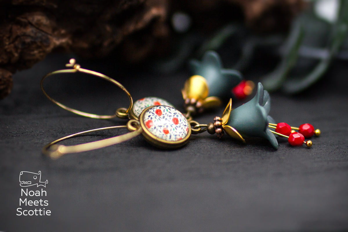 Lange Blütenohrringe im Vintage-Stil mit graugrünen Blüten, roten facettierten Glasperlen und bronzefarbenen Details.