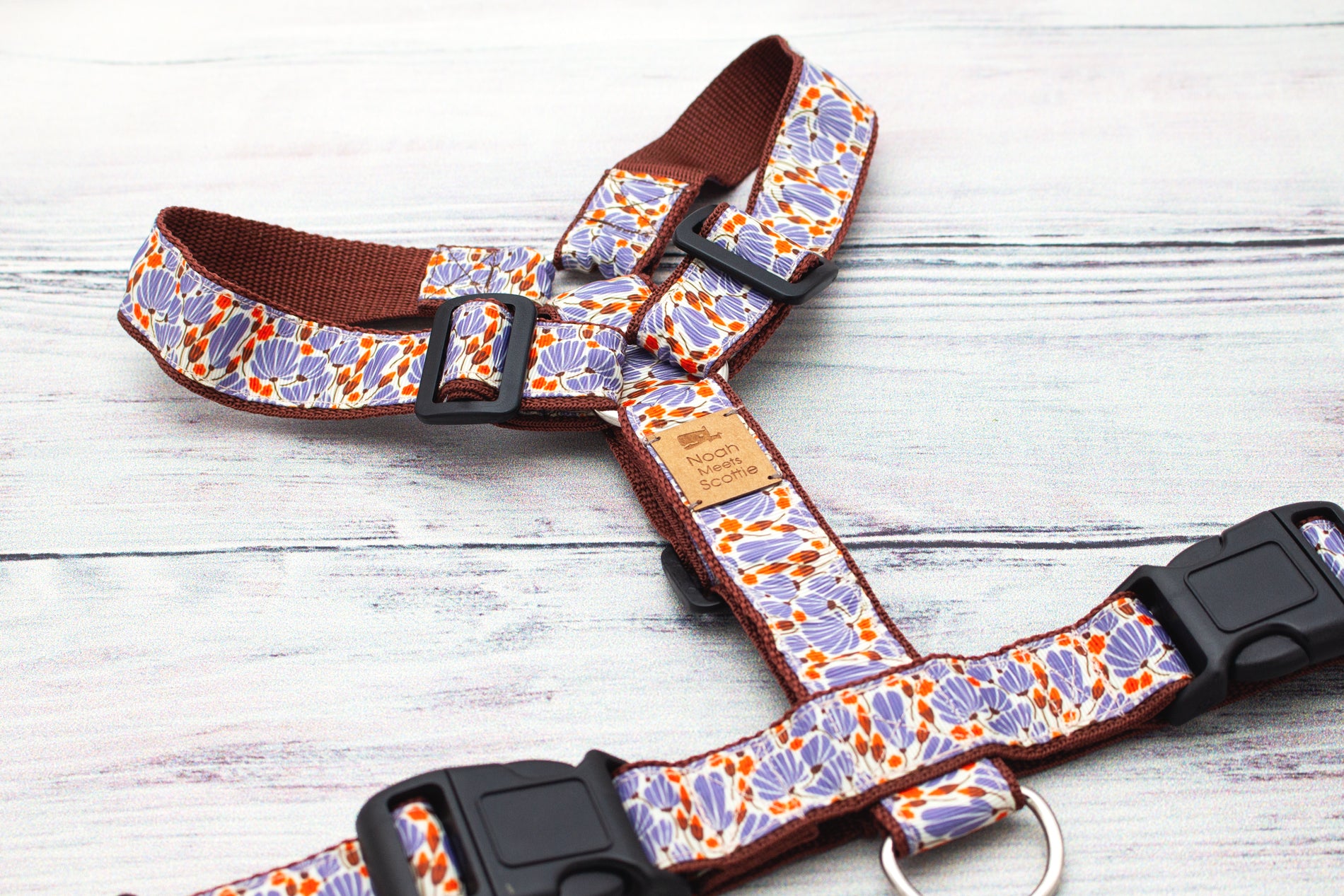 Detailaufnahme des Hundegeschirrs DANDELIGHT mit grafischen Pusteblumenformen in Lila und kleinen Punkten in Orange, hochwertiges Gurtband im warmen Naturton.