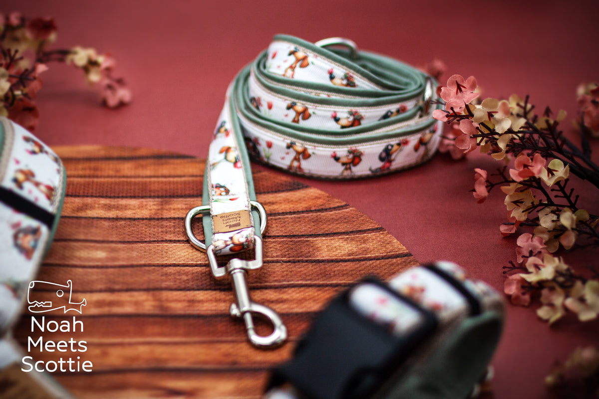 Verspieltes Hundegeschirr mit Hunde- und Blumenmotiv auf hellem Grund und salbeigrüner Kunstlederfütterung.