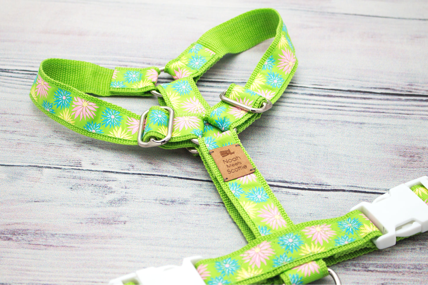 Detailaufnahme des Hundegeschirrs MIRA mit strahlenförmigen Blüten in Pastelltönen auf hellgrünem Band; farbechtes Muster im frühlingshaften, floralen Stil für stilvolles Hundezubehör.