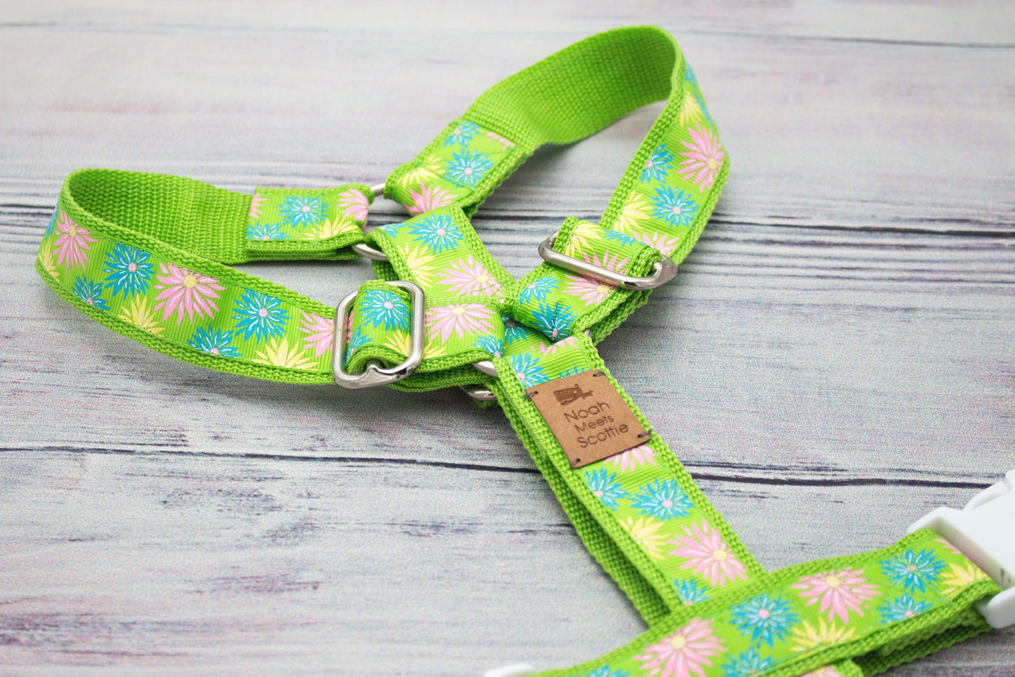 MIRA Hundegeschirr mit lebendigen Blütenmotiven in Pink, Blau und Weiß auf grünem Gurtband; modernes, leichtes Design im frühlingsinspirierten Look für hochwertige Hundemode.