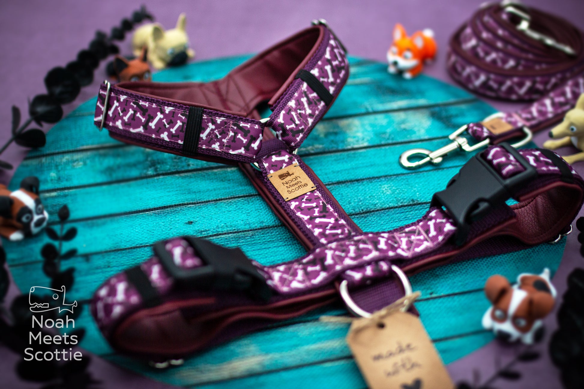 Nahaufnahme des Hundegeschirrs Paw a Bone mit kleinen weißen Hundeknochen auf auberginefarbenem Hintergrund.