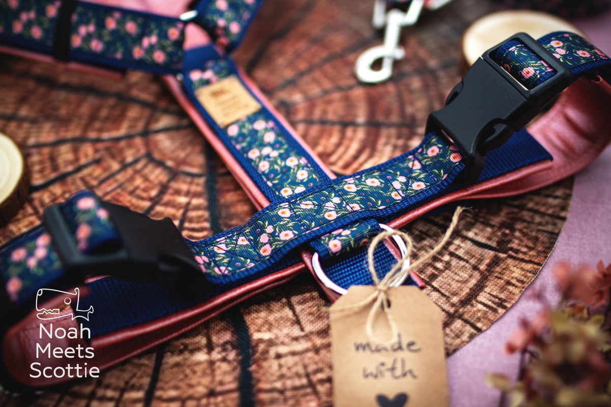 Nahaufnahme des dunkelblauen Hundegeschirrs mit vielen kleinen rosafarbenen Rosen und feinen floralen Details auf dem gemusterten Gurtband.