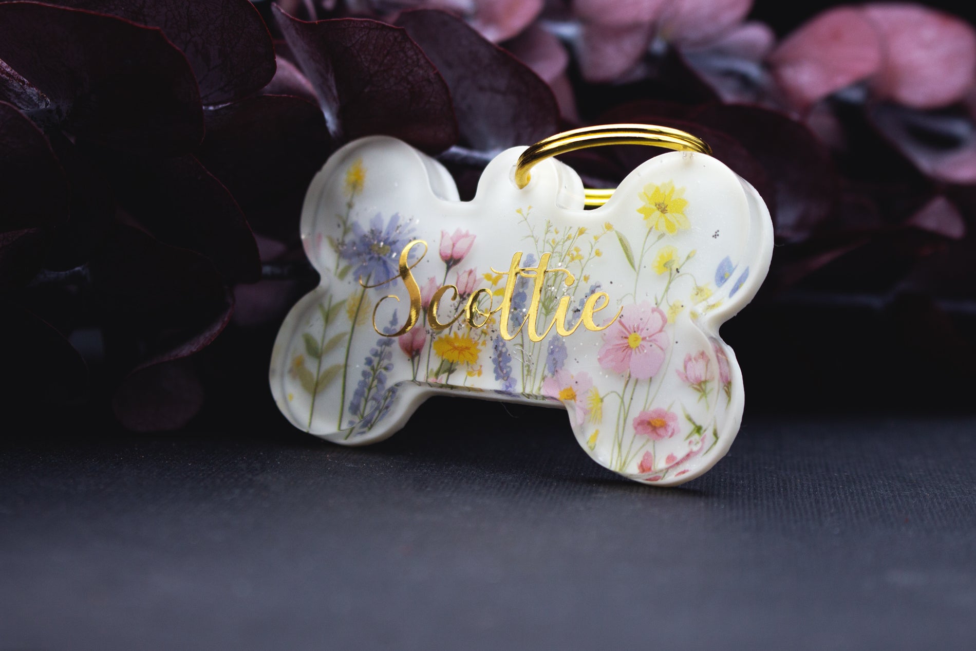 Detailaufnahme der Hundemarke EWIGBLÜTE mit filigranen Blüten in Pastell, Resin-Oberfläche, wetterfest, liebevoll handgefertigt.