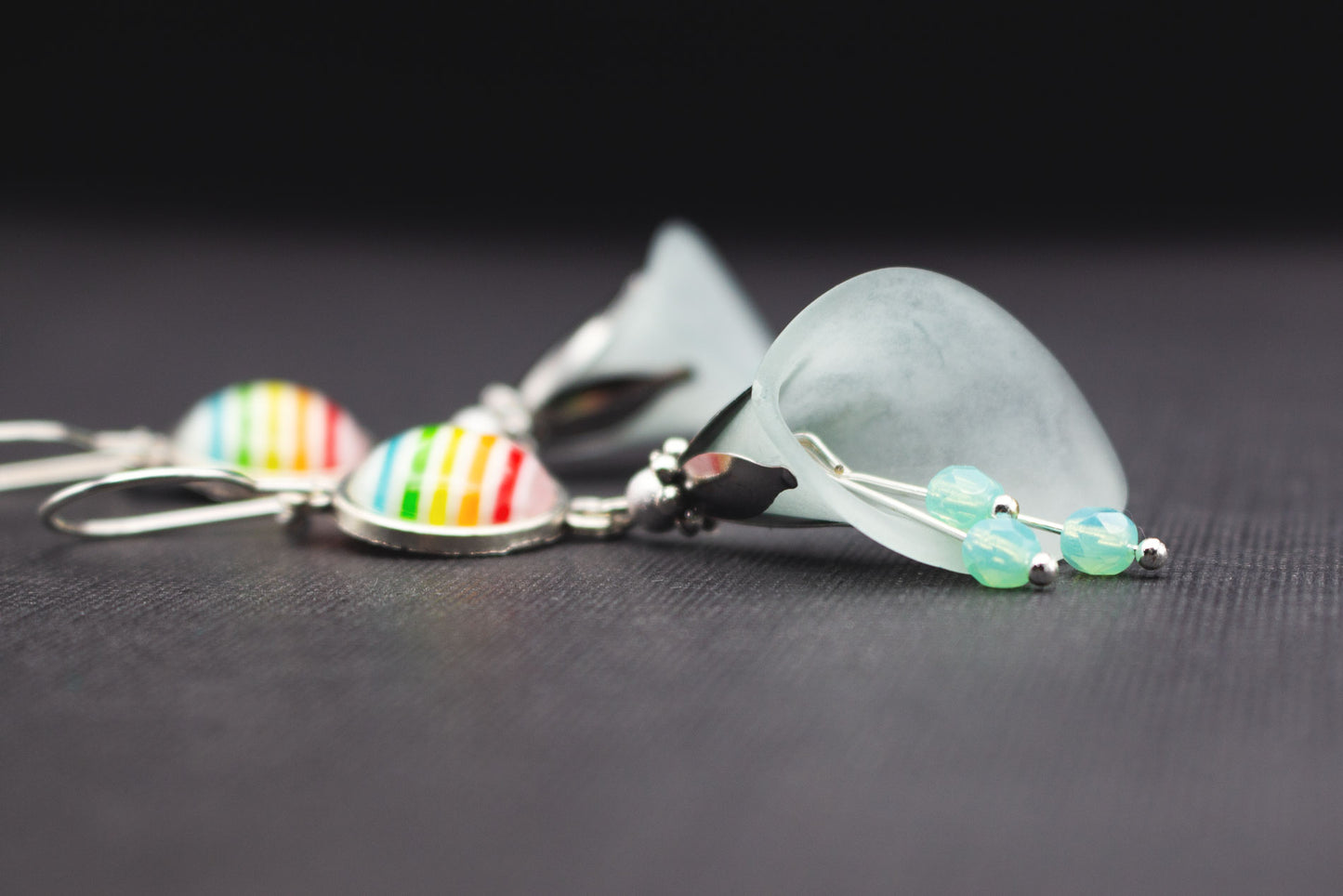 Seitliche Ansicht silberfarbener Ohrringe mit Eisblüten und Regenbogen-Cabochons