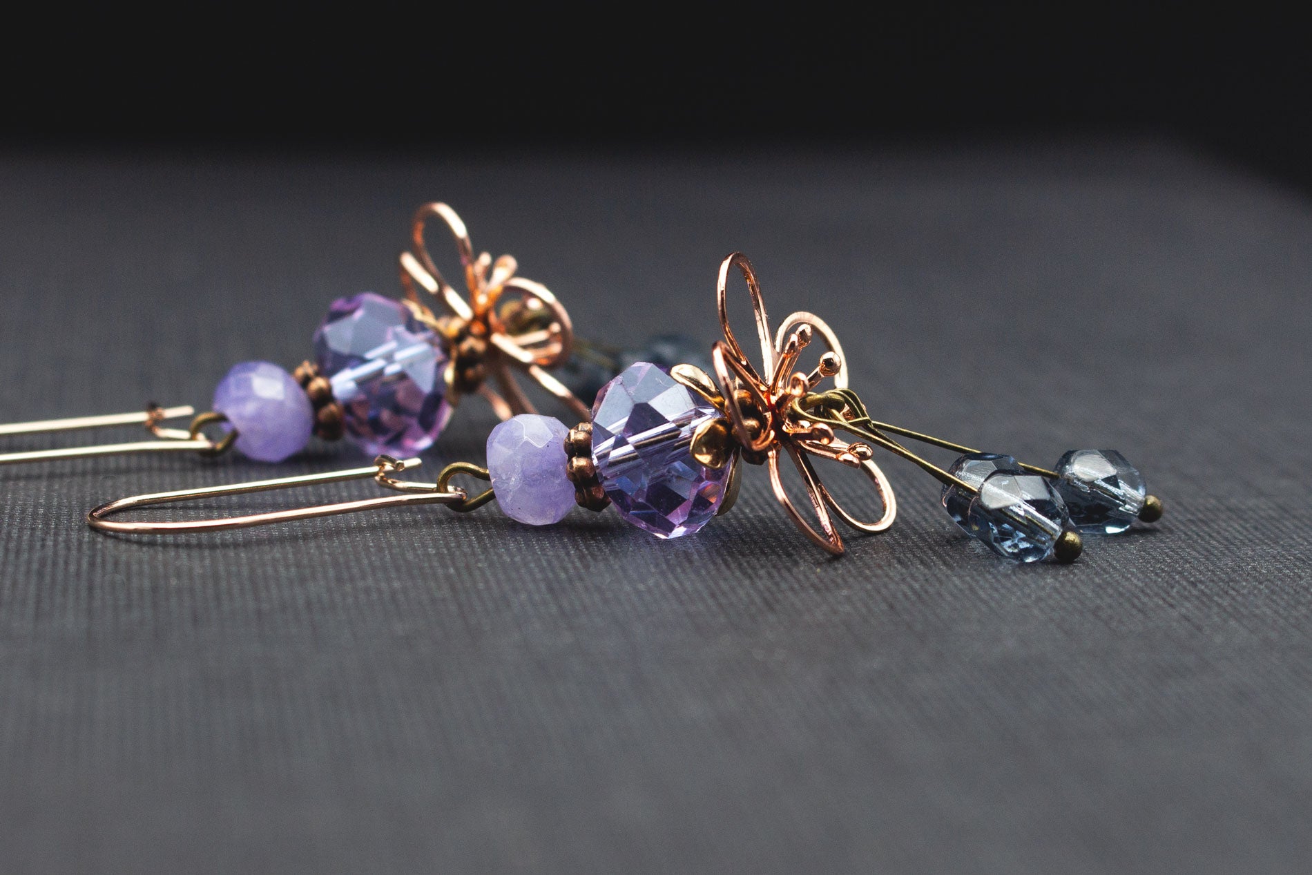 Detailansicht von fliederfarbenen und blauen Glasperlen mit roségoldfarbenen Blüten