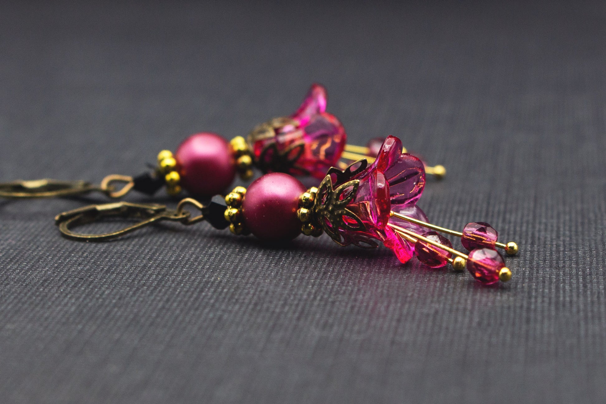 Seitliche Ansicht pinker Blütenohrringe mit Glasperlen und goldfarbenen Elementen