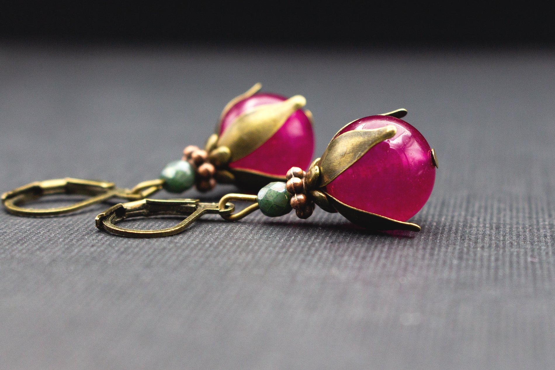 Elegante Ohrhänger mit fuchsiafarbenen Glasperlen, grünem Akzent und antik-bronzenem Metall