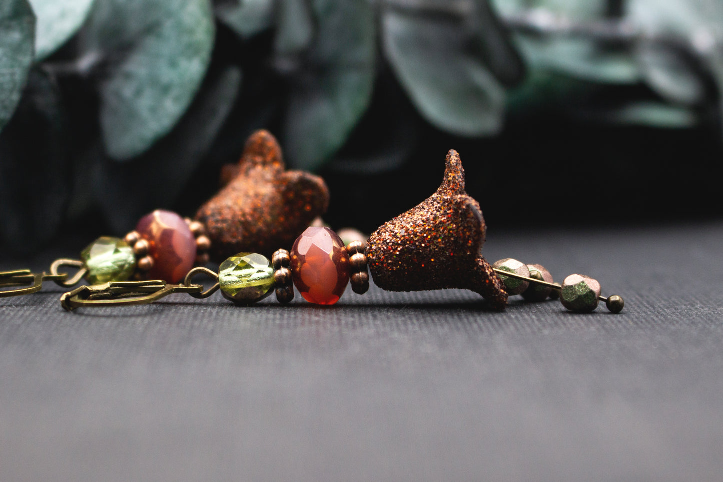 Detailansicht braun glitzernder Blüte mit Glasperlen in Rosé-Rot und Lindgrün an antik-bronzenem Metall