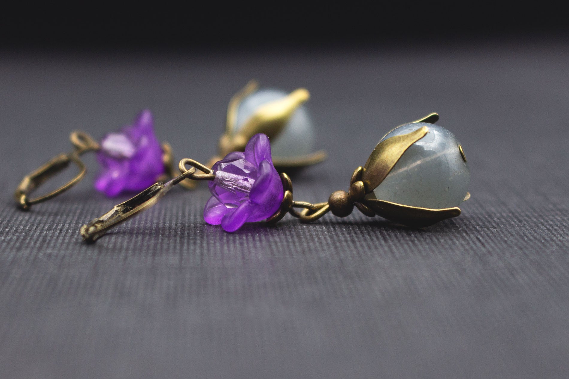 Detailansicht von grauen Glasperlen, lila Acrylblüte und violetter Glasperle