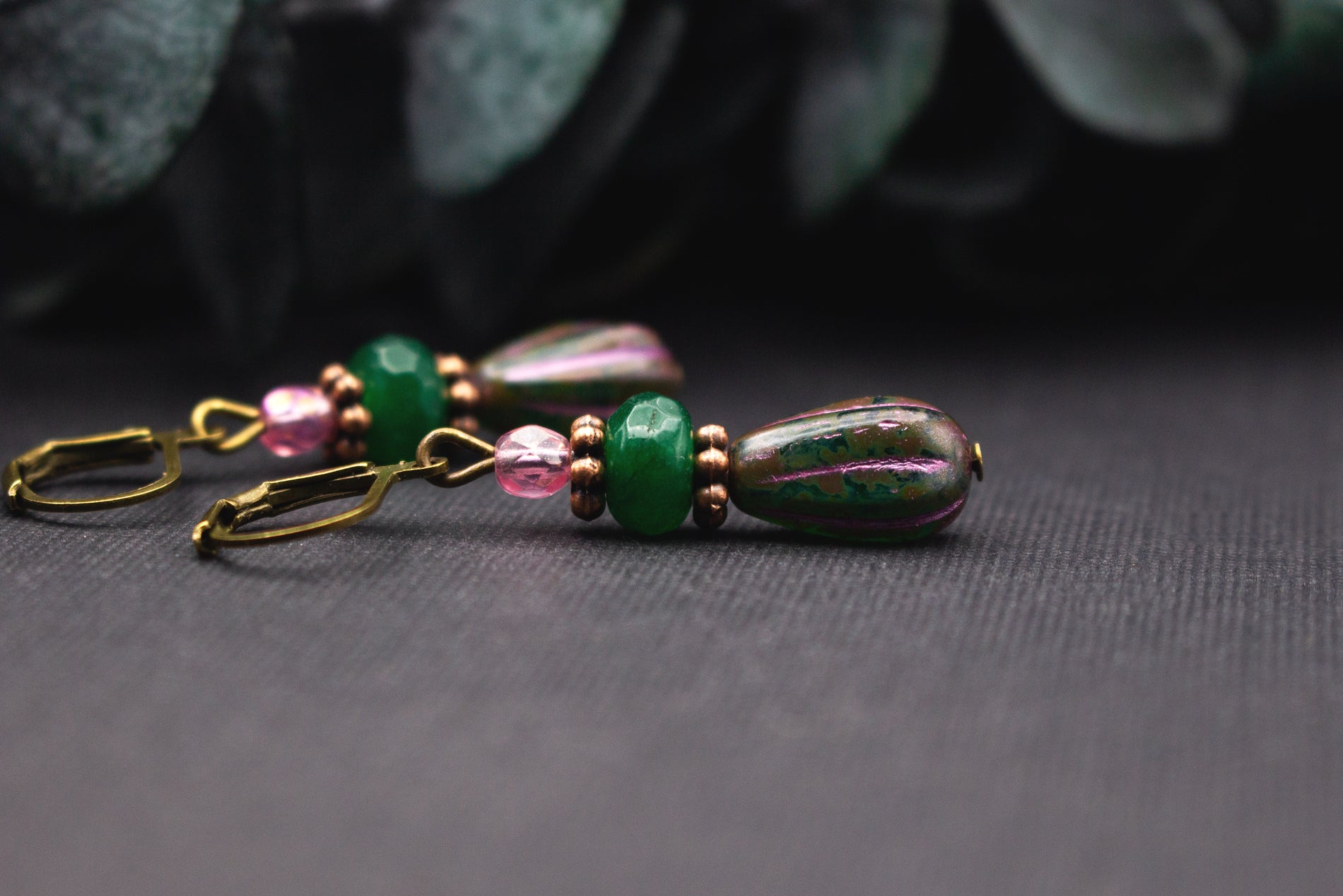 Detailansicht grüner und rosafarbener Glasperlen an Ohrhängern mit Kupferrot und Antik-Bronze