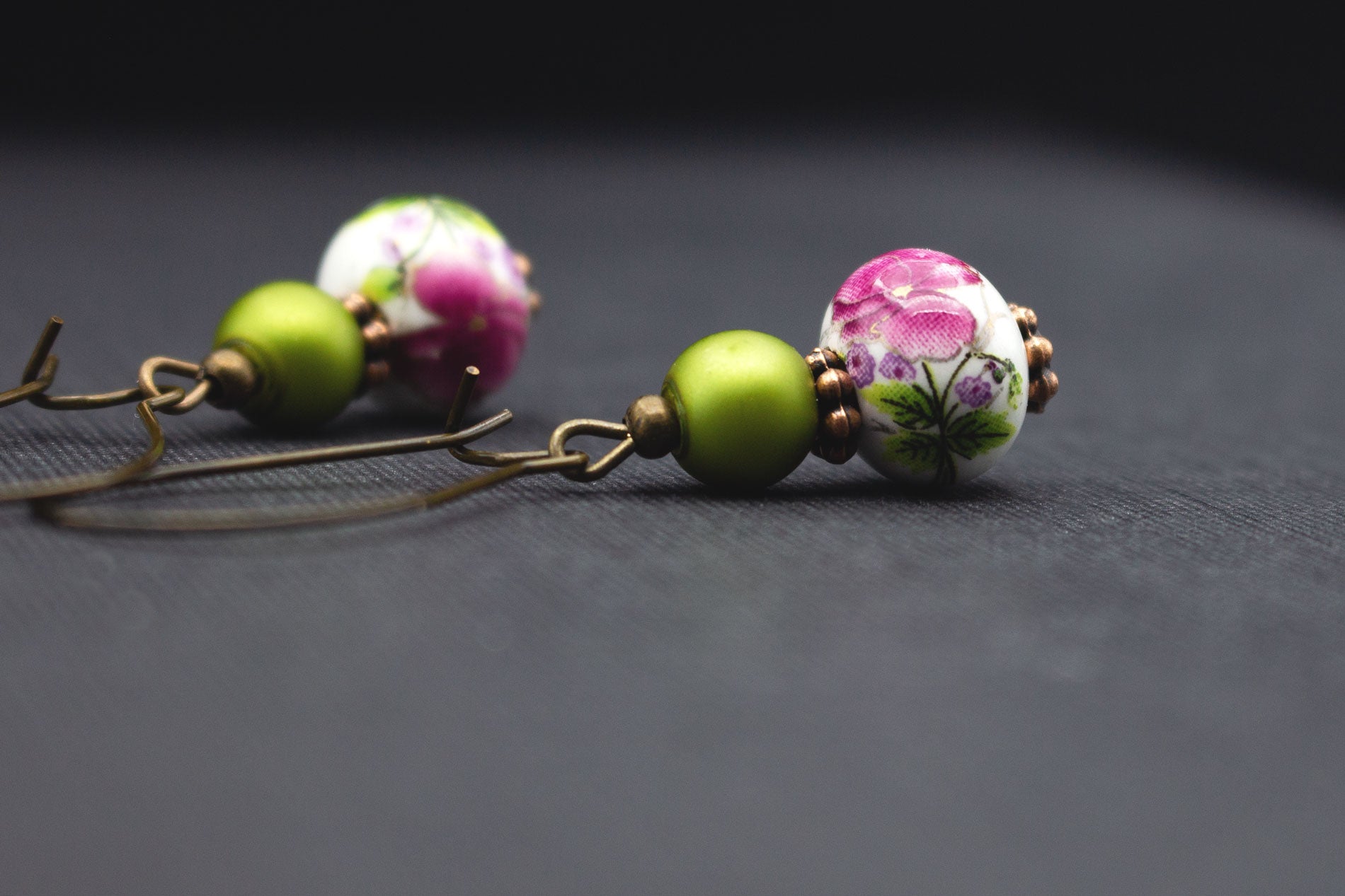 Detailansicht Keramikohrringe mit floralen Mustern in Pink und Glasperlen in Grün