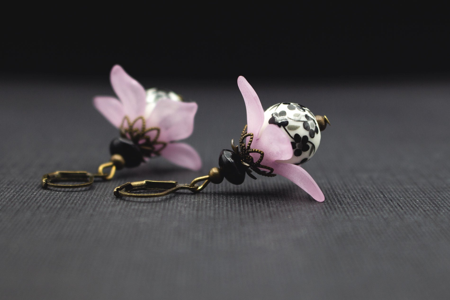 Detailansicht Ohrringe mit rosa Acryl-Kirschblüten und kunstvoll gemusterter Keramikperle