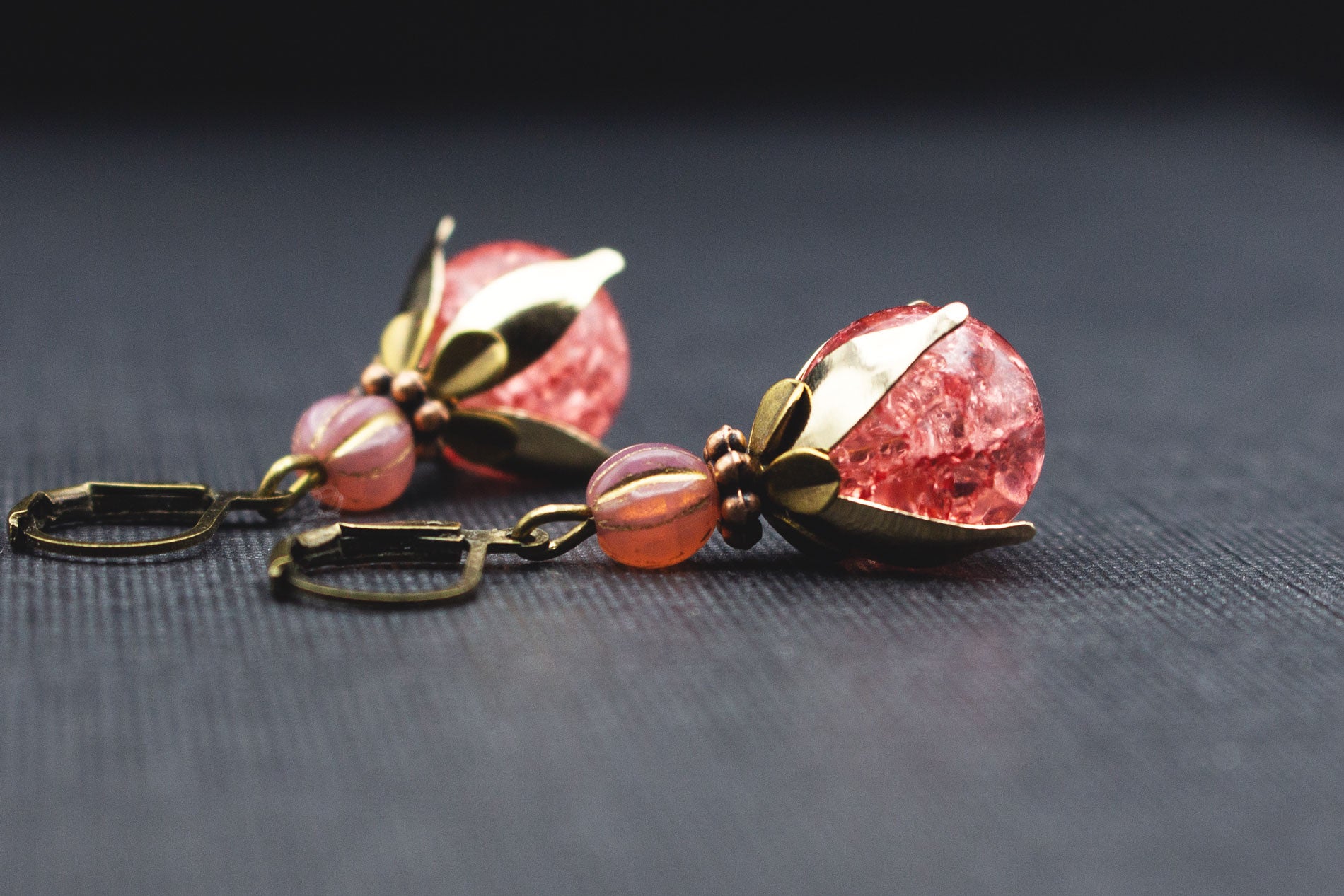 Seitenansicht von Ohrringen mit rosa Crackle-Glasperlen und goldfarbenen Perlenkappen