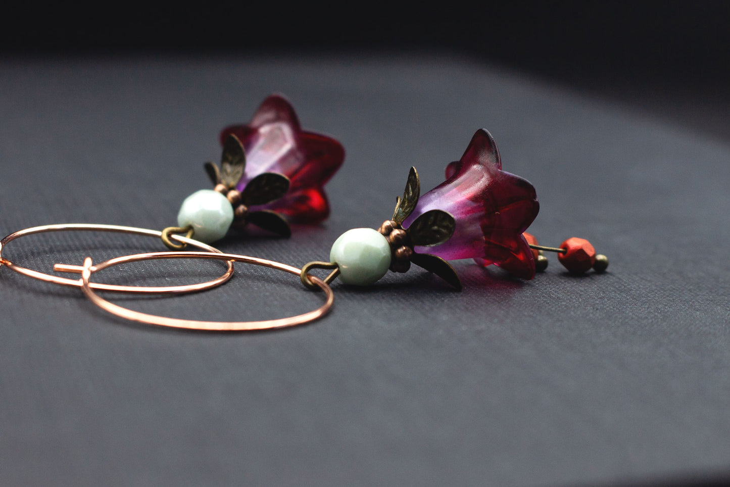 Seitenansicht Roségold-Creolen mit lila-roten Blüten und Glasperlen