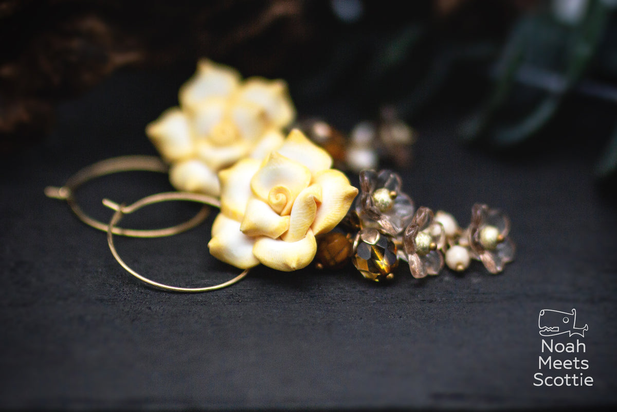 Florale Creolen mit plastischen Rosen in Vanillegelb, kleinen Blüten in Taupe und Grau sowie verschiedenen Perlendetails.