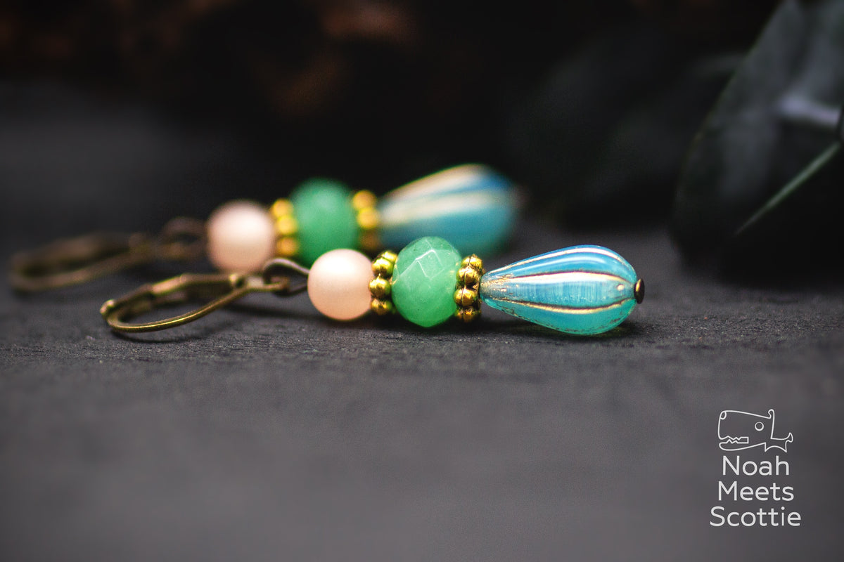 Türkise Tropfen Ohrringe mit geriffelter Melonenperle, grüner facettierter Perle, hellrosa Polarisperle und goldfarbenen Details.
